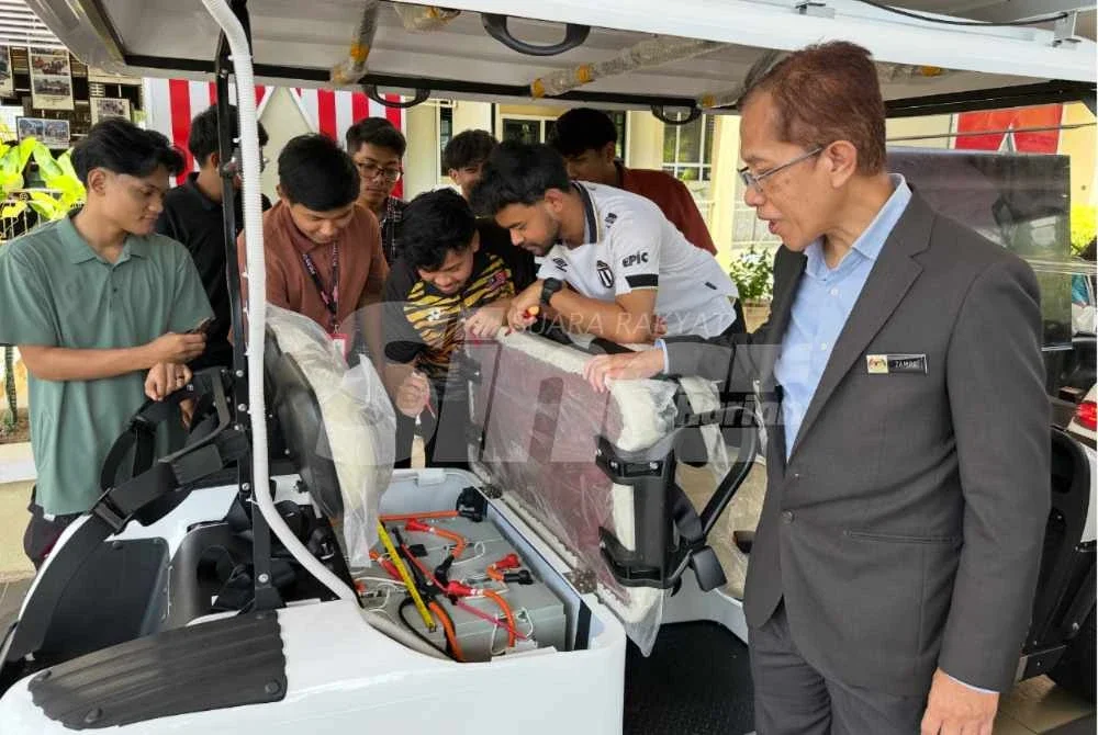 Mohd Zamre (kanan) melihat penuntut memeriksa bateri pada buggy solar.
