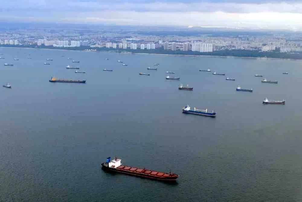 Kapal berlayar berhampiran deretan kapal yang berlabuh di perairan Singapura di pintu masuk Selat Melaka. 
