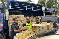 Hanif (tengah) menunjukkan minyak masak paket bersubsidi yang dirampas pihak berkuasa di kawasan Bachok. FOTO: ADILA SHARINNI WAHID