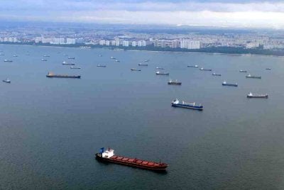 Kapal berlayar berhampiran deretan kapal yang berlabuh di perairan Singapura di pintu masuk Selat Melaka. 