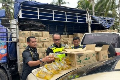 Hanif (tengah) menunjukkan minyak masak paket bersubsidi yang dirampas pihak berkuasa di kawasan Bachok. FOTO: ADILA SHARINNI WAHID