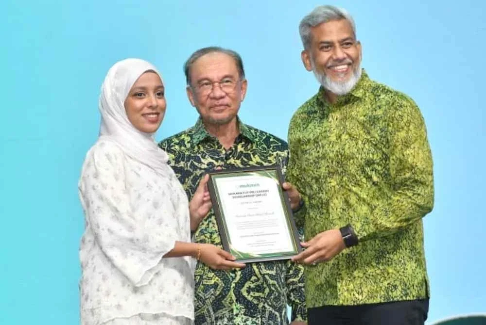 Seorang pelajar, Razinah Abdul Manaf, menerima biasiswa MUKMIN Future Leaders Scholarship (MFLS) untuk melanjutkan pengajian dalam bidang pergigian dari Presiden MUKMIN, Datuk Wira Shahul Dawood, disaksikan oleh Perdana Menteri, Datuk Seri Anwar Ibrahim.