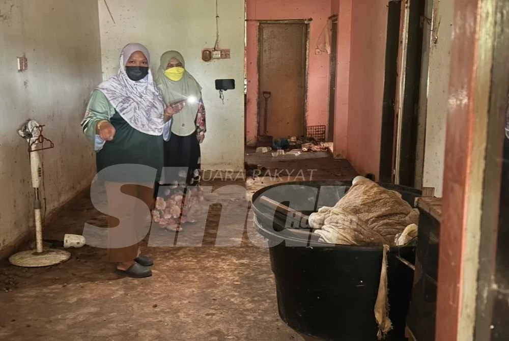 Nurul Farhana (kiri) melihat keadaan rumahnya yang kotor dan busuk.
