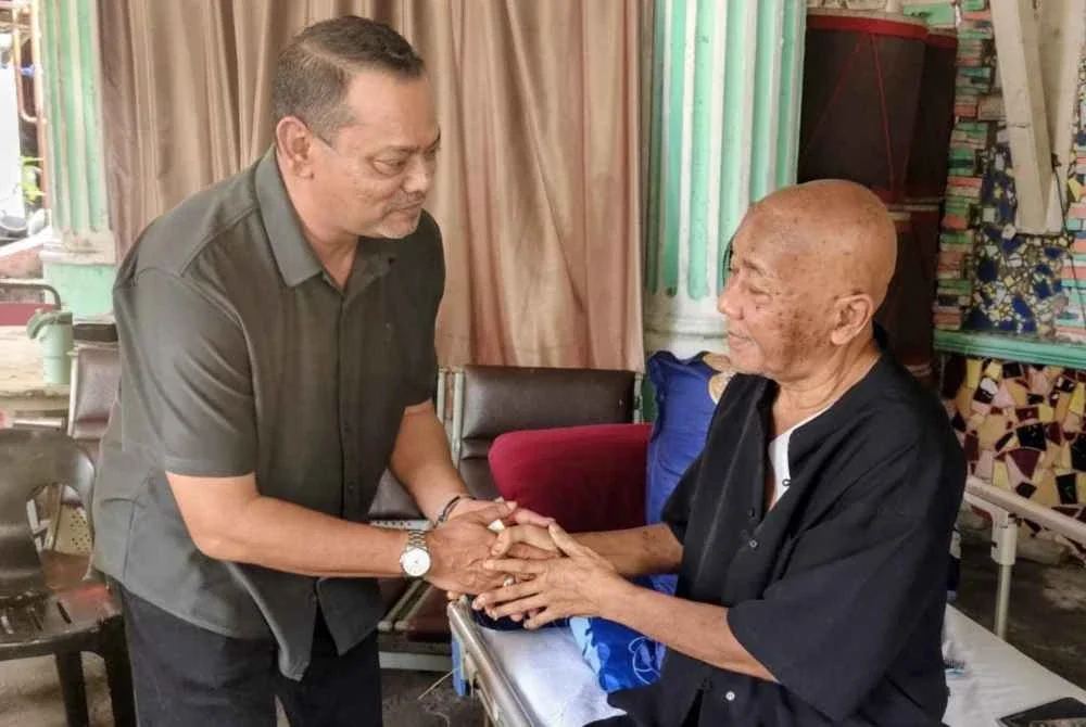 Rosli (kiri) menyampaikan sumbangan kepada Rosli ketika mengunjungi komposer itu di kediamannya.