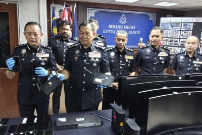 Ab Rahaman (dua dari kiri) menunjukkan barangan yang dirampas daripada sindiket calling center.