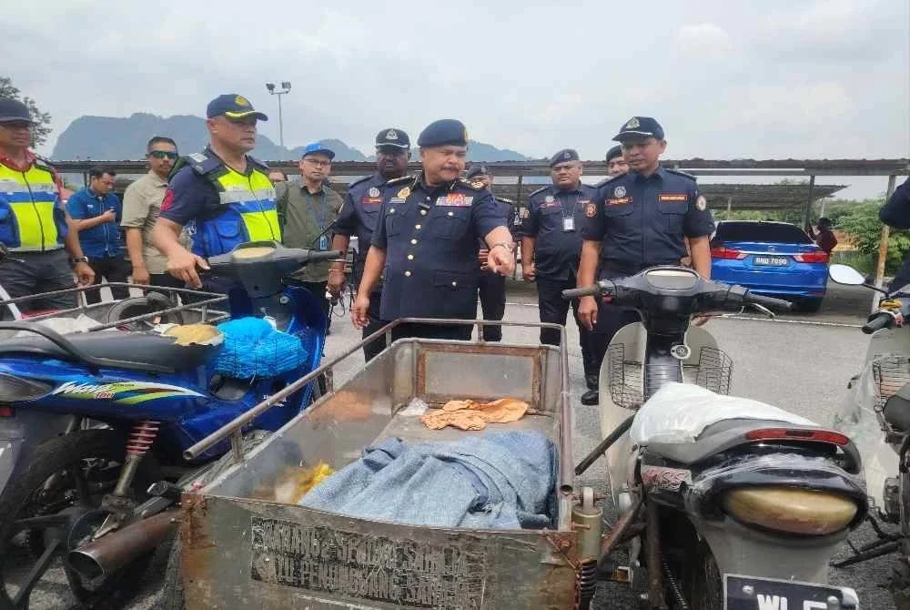 Ahmad Kamarunzaman (tengah) menunjukkan motosikal roda tiga yang disita JPJ pada Rabu. 
