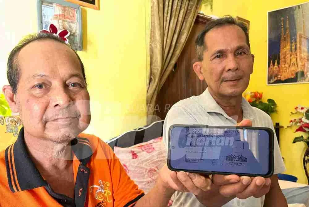 Mohd Affandi (kanan) menunjukkan kad pengenalan arwah bapanya sebagai petunjuk menjejaki abang sulungnya yang terpisah sejak 50 tahun lalu.