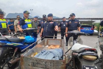 Ahmad Kamarunzaman (tengah) menunjukkan motosikal roda tiga yang disita JPJ pada Rabu. 