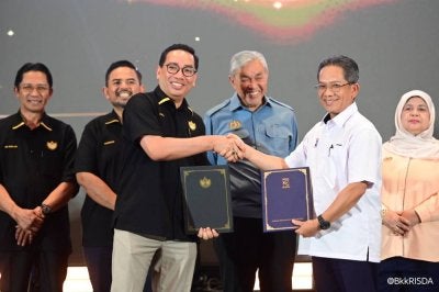 Ahmad Zahid menyaksikan pertukaran dokumen MoU antara Zainal Azni (hadapan, kiri) dan Pengurus Besar KESEDAR, W Muhd Rahimi Wan Salleh (kanan).