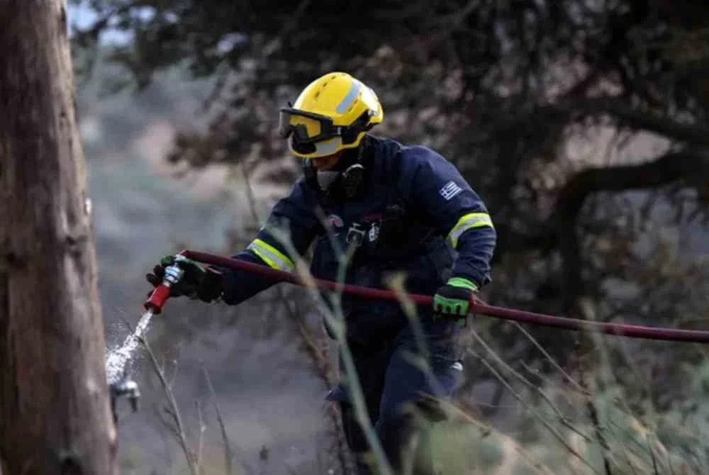 Seorang anggota bomba berusaha memadamkan kebakaran hutan yang marak berhampiran Kampung Krya Vrysi di pulau Crete, Greece. Foto Reuters 