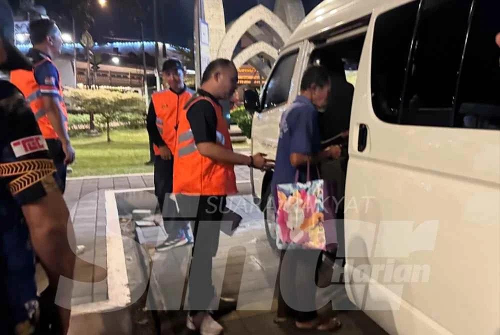 Pok Mat (kanan) yang dibawa ke dalam van pihak berkuasa untuk diselamatkan. - Foto: SINAR HARIAN/ ADILA SHARINNI WAHID