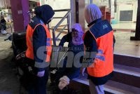 Wanita warga Thailand (tengah) yang dipercayai duduk di kaki lima bank untuk mengemis.
