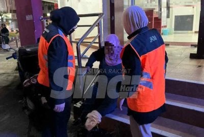Wanita warga Thailand (tengah) yang dipercayai duduk di kaki lima bank untuk mengemis.
