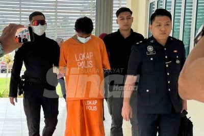 Polis mengawal ketat tertuduh (dua dari kiri) ketika berjalan menuju ke lokap mahkamah.
