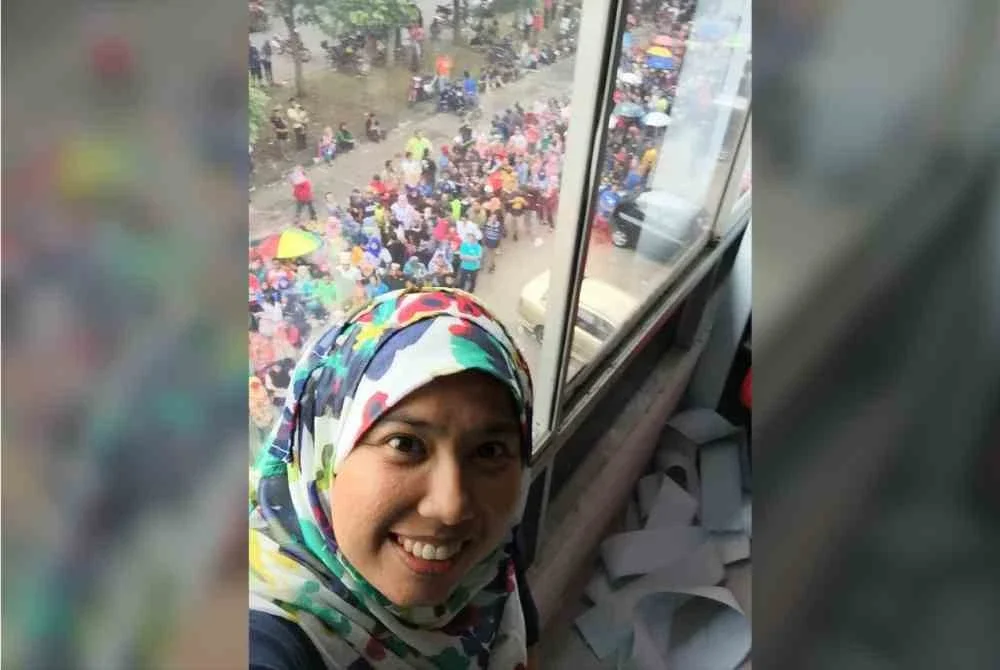 Norashikin menunjukkan orang ramai yang sanggup beratur walaupun ketika hujan.