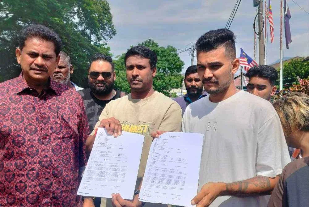 Thayaalaraj (dua dari kiri) dan Sasindran menunjukkan salinan laporan polis yang dibuat di Balai Polis Kampung Bharu Buntong di sini pada Jumaat.