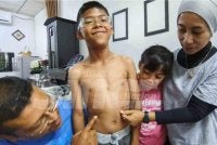Safinatul Hayah (kanan) dan Mohd Zamani (menunjukkan parut pembedahan 11 tahun lalu yang masih kelihatan di badan Muhammad A'Ariz Daniel.