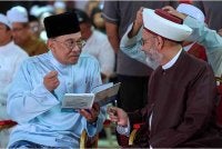 Anwar bersama tokoh pendakwah Sheikh Khaleel Ismael Elias melihat buku Terjemahan Tafsir Surah Al-Insan karya Sheikh Khaleel pada Majlis Kuala Pilah Berselawat dan Munajat Perdana Negeri Sembilan di Dataran Melang hari ini. Foto Bernama 