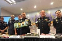 Abd Halim (dua dari kanan) menunjukkan wang tunai yang dirampas menerusi Op Crack membabitkan sindiket godam MyIMMs. 