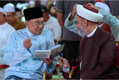 Anwar bersama tokoh pendakwah Sheikh Khaleel Ismael Elias melihat buku Terjemahan Tafsir Surah Al-Insan karya Sheikh Khaleel pada Majlis Kuala Pilah Berselawat dan Munajat Perdana Negeri Sembilan di Dataran Melang hari ini. Foto Bernama 