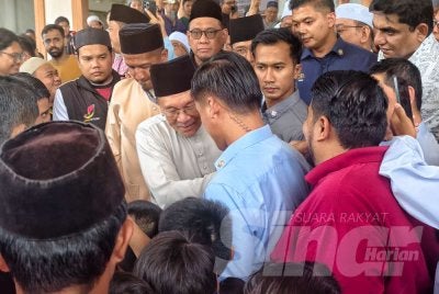 Anwar (tengah) dikerumuni sebaik selesai menunaikan solat Jumaat di Masjid Kariah Paroi Jaya.