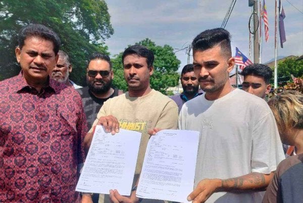 Thayaalaraj (dua dari kiri) dan Sasindran menunjukkan salinan laporan polis yang dibuat di Balai Polis Kampung Bharu Buntong di sini pada Jumaat.