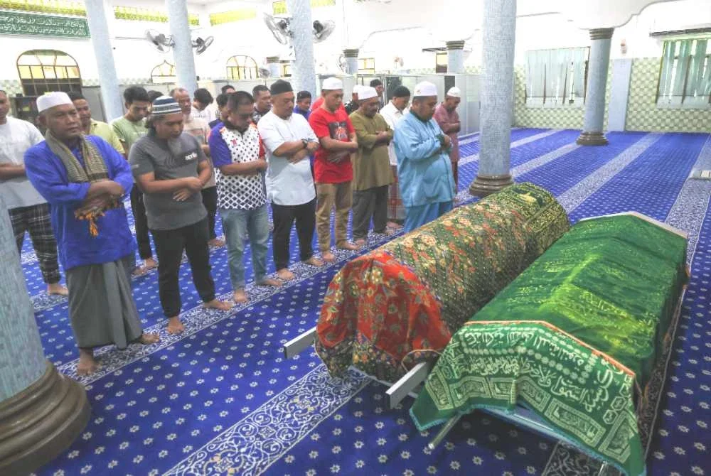 Ahli keluarga dan penduduk kampung bersama-sama menunaikan solat jenazah Allahyarham Maria dan anak bongsunya, Muhammad Ziekyr Iman sebelum dikebumikan dalam satu liang lahad di Tanah Perkuburan Islam Kampung Melor Lama pada 10.30 pagi. Foto Bernama