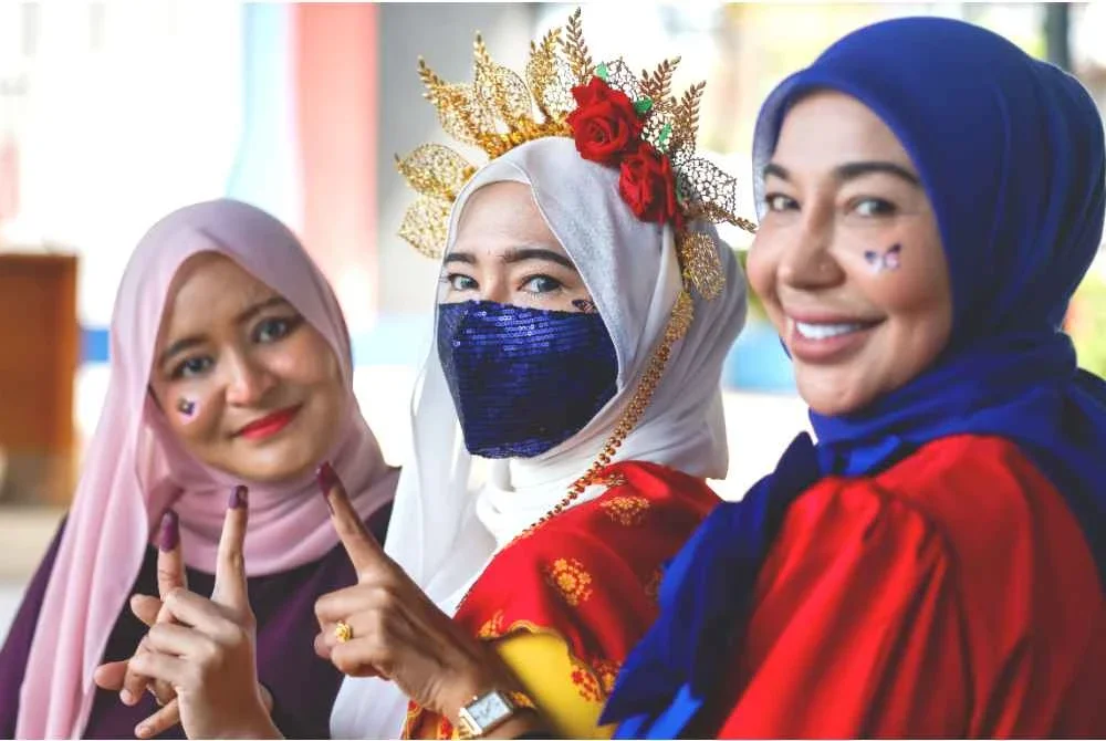 (Dari kiri) Nadzifah, Bahirah dan Zamzarina tampil mengenakan busana bertemakan Jalur Gemilang sebagai tanda semangat patriotik sempena sambutan Bulan Kebangsaan ketika menjalankan tanggungjawab mengundi di SJKC Chung Hua, Rantau. Foto Bernama