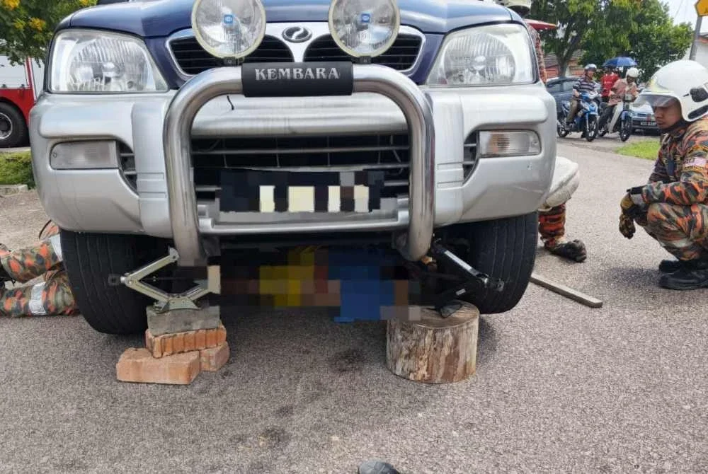 Anggota bomba berusaha menyelematkan mangsa yang tersepit di bawah kenderaan dibaikinya.