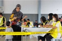 Seorang pengundi berbual dengan anak lelakinya ketika menunaikan tanggungjawab mengundi pada Hari Pengundian PRN Negeri Sembilan di pusat mengundi SJKC Chung Hua, Rantau pada Sabtu. Foto Bernama