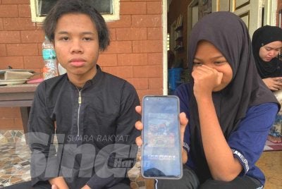 Nur Kasih dan abangnya, Muhammad Aiman Ashraf tidak dapat menahan sebak ketika menunjukkan gambar arwah ibu dan adiknya yang maut dalam kemalangan di Jalan Gua Musang-Kuala Krai berhampiran Gua Sejuk, Gua Musang.