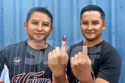 Izzat Ismir (kiri) dan Izzat Izwan menunjukkan jari mereka yang telah dicelup dengan dakwat selepas selesai mengundi.