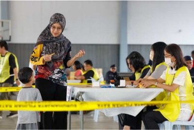 Seorang pengundi berbual dengan anak lelakinya ketika menunaikan tanggungjawab mengundi pada Hari Pengundian PRN Negeri Sembilan di pusat mengundi SJKC Chung Hua, Rantau pada Sabtu. Foto Bernama
