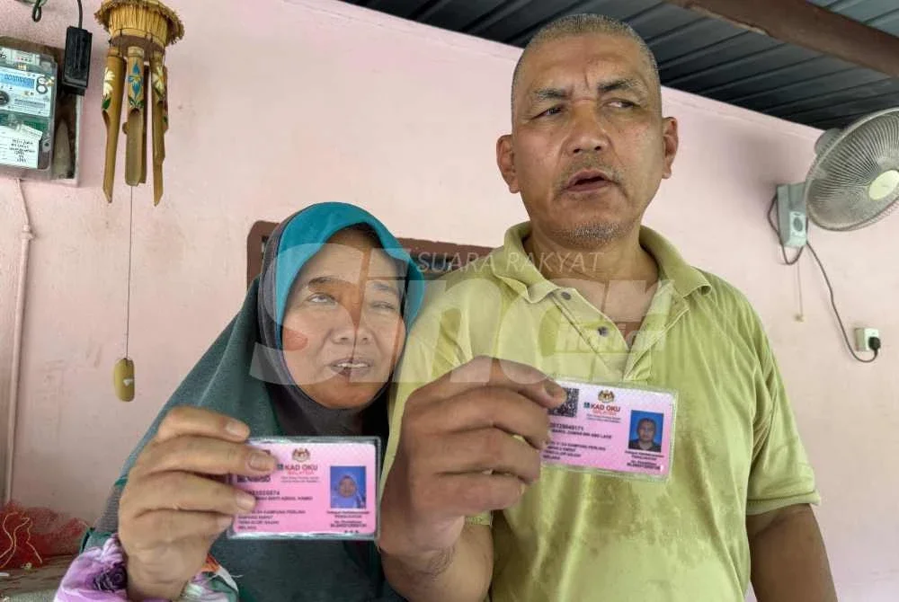 Kamarul Zaman dan isteri menunjukkan kad OKU dimiliki mereka.