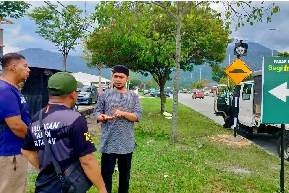 Hafez (kanan) berbincang sesuatu bersama wakil penduduk selepas melihat kerja-kerja pemasangan papan tanda bonggol yang dibina di Lebuh Chepor Utama 2 di sini.