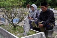 Ismail ditemani isteri meluangkan masa menziarahi pusara ibu dan bapanya di Tanah Perkuburan Islam Tebing Tinggi pada Ahad. Foto Bernama 