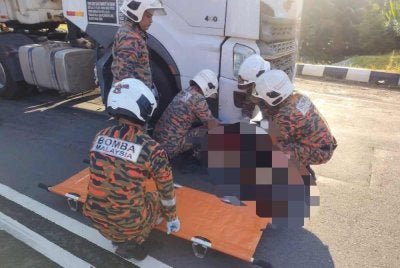 Anggota bomba membawa keluar mangsa yang tersepit di bawah kepala lori dalam satu kemalangan di Jalan Labis-Segamat.