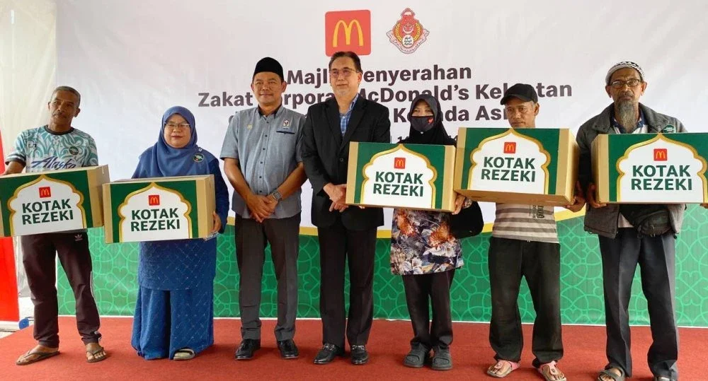 Ahmad Shihafuddin (tiga dari kiri) dan Mohd Anis (empat dari kiri) bersama penerima Kotak Rezeki berisi barangan keperluan harian sumbangan McDonald’s Malaysia.