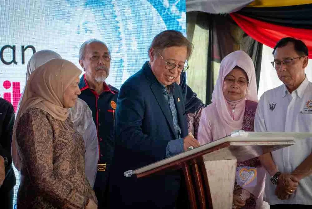 Abang Johari yang diiringi Nancy menandatangani plak perasmian Anjung Kasih Hospital Bintulu pada Isnin.