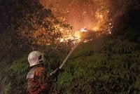 Anggota bomba sedang memadamkan kebakaran hutan di Sepang pada Isnin.