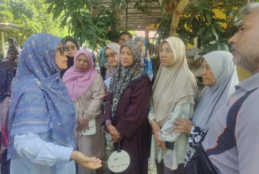Mariam (kiri) bertemu dengan penduduk terjejas semasa meninjau kawasan kediaman penduduk yang terjejas.