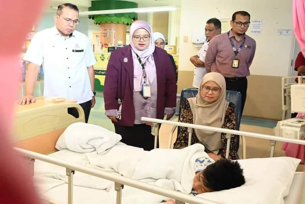 Khairul Amri (kiri) mengiringi Sabariah (duduk, kanan) menziarahi anak kepada arwah Mohd Radzi yang terselamat dalam tragedi pokok tumbang di Bentong di HOSHAS pada Selasa. 