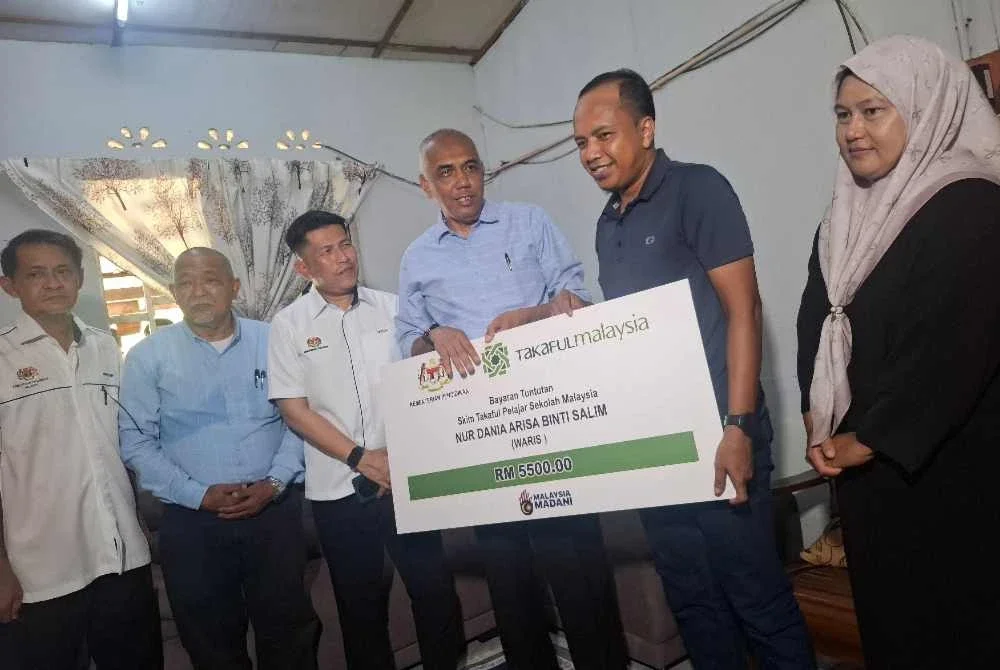 Khairudin (empat dari kiri) menyerahkan cek cura wang tuntutan Skim Takaful Pelajar Sekolah Malaysia (TPSM) berjumlah RM5,500 kepada Salim.