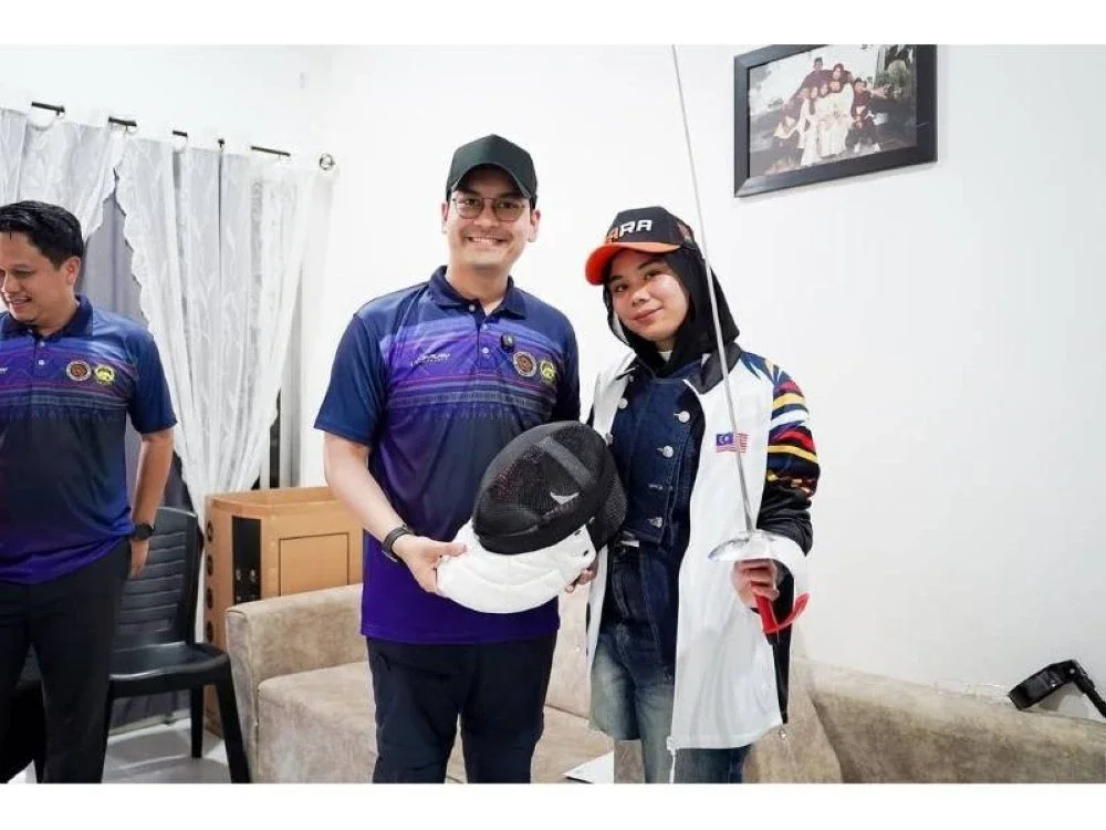 Dr Mohammed Taufiq menyampaikan peralatan sukan lawan pedang kepada Nik Haziera.