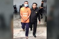 Suspek (kiri) dikawal anggota SPRM ketika keluar dari lokap mahkamah selepas selesai mengambil perintah reman. Foto: SPRM
