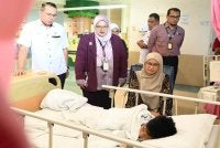 Khairul Amri (kiri) mengiringi Sabariah (duduk, kanan) menziarahi anak kepada arwah Mohd Radzi yang terselamat dalam tragedi pokok tumbang di Bentong di HOSHAS pada Selasa. 