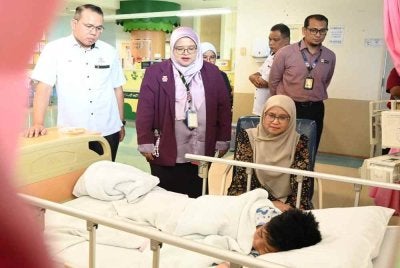Khairul Amri (kiri) mengiringi Sabariah (duduk, kanan) menziarahi anak kepada arwah Mohd Radzi yang terselamat dalam tragedi pokok tumbang di Bentong di HOSHAS pada Selasa. 