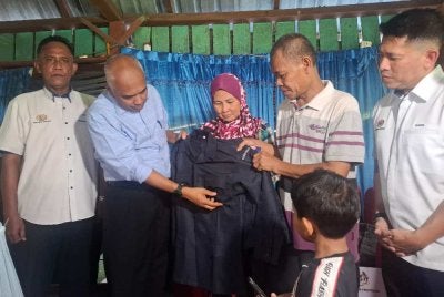 Khairudin (dua dari kiri) melihat sehelai baju uniform Kadet Polis milik Allahyarham Nur Atikah yang kini menjadi pengubat rindu keluarganya.