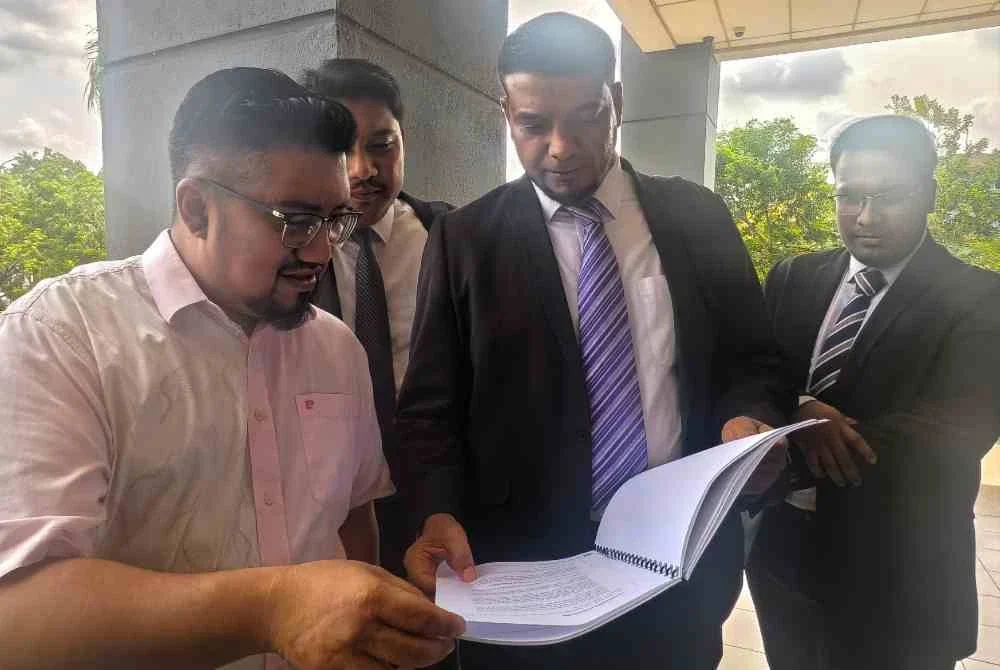 Muhammad Rafique menunjukkan dokumen kepada Chegubard (kiri) ketika di Kompleks Mahkamah Seremban.