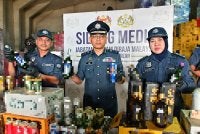 Jamal (tengah) menunjukkan minuman keras yang dirampas. Foto: JKDM